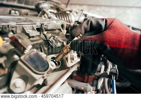 A Auto Mechanic Is Installing Automobile Iridium Spark Plugs Into The Ignition Socket Of The Engine 