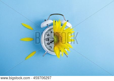 Sunflower On The Alarm Clock Face On The Blue Background. Copy Space. Top View.