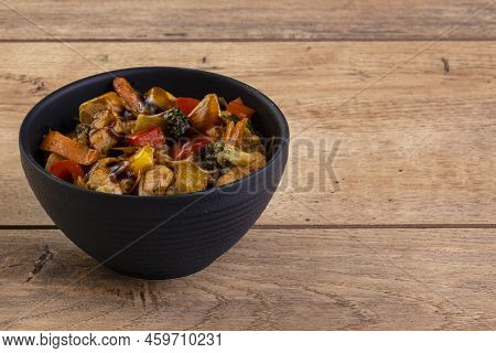 Chicken Yakissoba In Black Ceramic Bowl On Wooden Table.