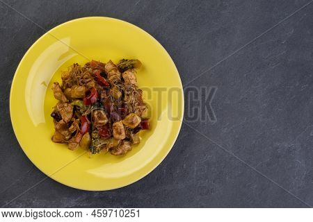 Yakisoba With Chicken Meat On A Yellow Plate On A Dark Slate Stone - Top View