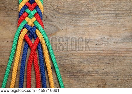 Top View Of Braided Colorful Ropes On Wooden Background, Space For Text. Unity Concept