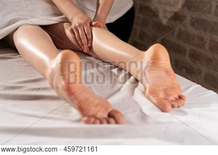 Masseur Massaging Female Legs In A Beauty Salon. Cosmetic Treatment Concept. Relaxing Body Treatment