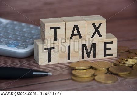 Tax Time Text On Wooden Blocks With Gold Coins, Pen And Calculator. Tax Concept.