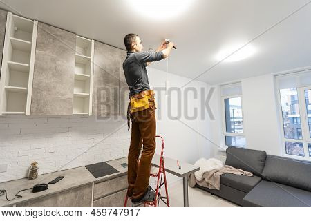 Electrician, A Male Electrician Is Standing On The Stairs Holding Wiring In His Hands And Stripping,