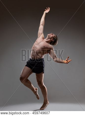 Young Muscular Man In An Expressive Pose, Throwing His Hands Up. Beautiful Muscles. Extraordinary At