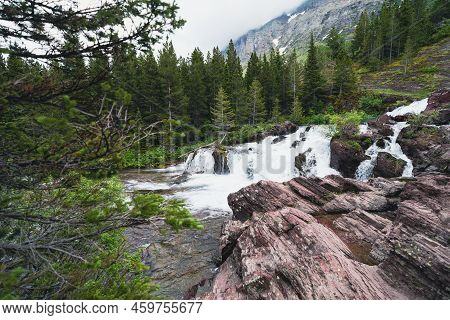 Redrock Falls Along Swiftcurrent Pass Hiking Trail In Glacier National Park On An Overcast Day