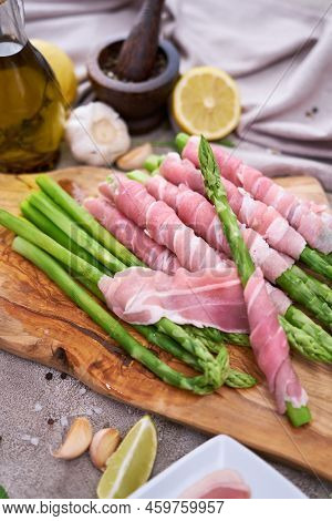 Cooking Green Aspargus Covered With Bacon At Domestic Kitchen