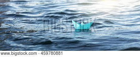 Close-up  A Small Origami Paper Boat In A Blue River Or Sea Water. The Concept Of Travel, Discoverie