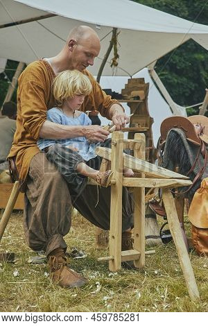 Højbjerg, Denmark, August, 2022: Retro Photo. Father Carpenter Teaching Son At The Viking Festival