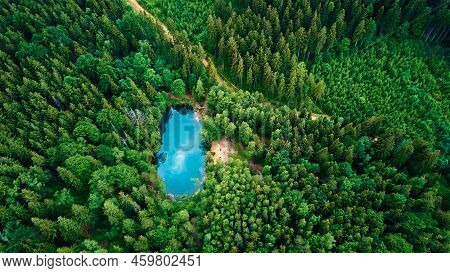 Blue Lake In The Middle Of Green Forest, Aerial View. Wild Colorful Lake In Mountain Park In Poland.