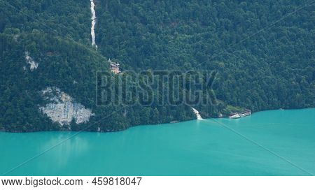 Giessbach Falls And Historic Hotel. Ship Waiting At The Shore Of Turquoise Lake Brienz.