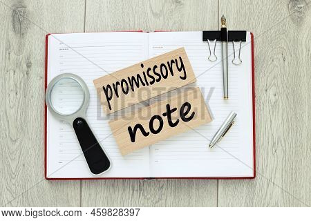 Promissory Note. Wooden Blocks With Text. On A Red Notebook