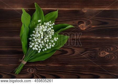 Small And Fragrant Spring Flowers. Bouqet Of Lily Of The Valley Flowers On Dark Wooden Background.