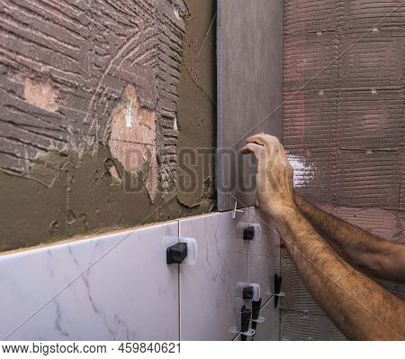 Laying Wall Ceramic Tile. Renovating The Wall. Construction Worker Laying Tile Over Concrete Wall Us
