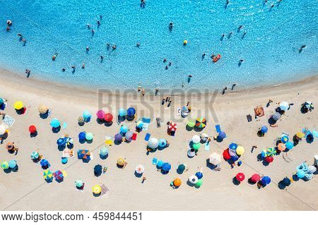 Aerial View Of Colorful Umbrellas On Beach, People In Blue Sea