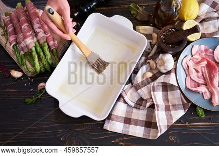 Ceramic Baking Dish For Cooking Aspargus Covered With Bacon On Wooden Kitchen Table