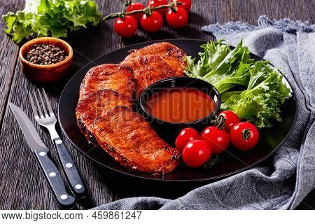 Grilled Slices Of Pork Loin Marinated In Paprika Based Sauce With Fresh Tomatoes And Lettuce Leaves 