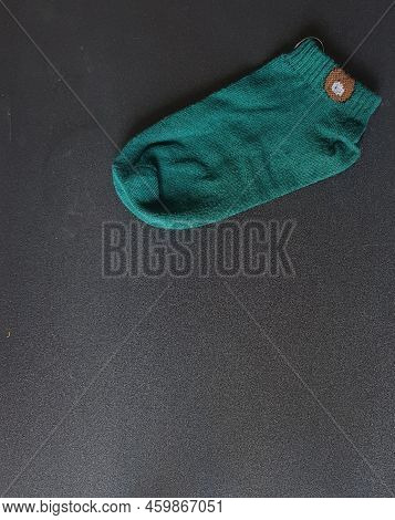 A Green Sock On A Black Background.