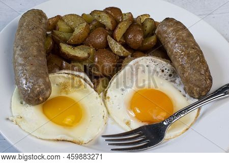 Two Fried Eggs Served With Italian Sausage And Homefries