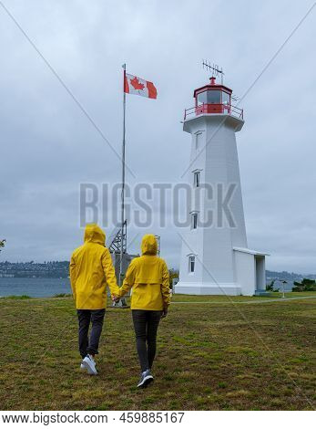 Quadra Island Old Historical Lighthouse At Cape Mudge Vancouver Island, Canada. Couple In Yellow Rai