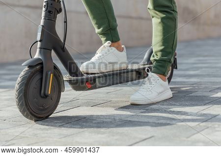 Woman In White Sneakers Is Standing On Electric Scooter