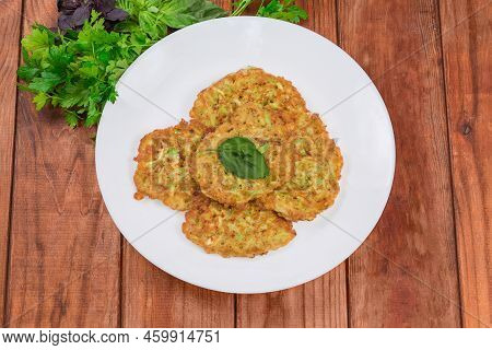Fried Small Thick Savory Pancakes Made With Grated Zucchini Decorated With Fresh Basil Leaf On The W