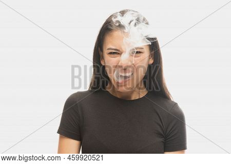 Angry Young Girl With Dark Hair Releases Smoke From The Mouth Isolated Over White Background. Concep