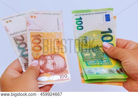 Euro And Kuna In The Hands Of A Banker Close-up On A White Background. Banknotes Of Different Denomi