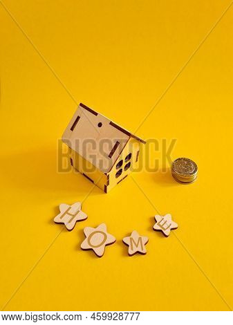 A Mini-house Next To A Stack Of Coins. The Concept Of Investment Property.