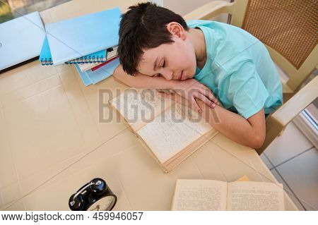 Top View Of A Tired Sleepy Schoolboy Falling Asleep On A Textbook While Doing Homework. Homeschoolin