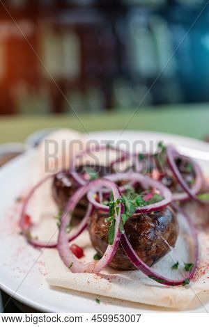 Georgian Fried Pork Sausages Kupaty With Onion, Cilantro On Pita On White Plate