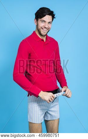 Youth Funny Concepts. Caucasian Handsome Brunet Man In Striped Underware Pulling Pants While Looking
