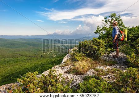 Young hiking man in the rays of sunset, standing at the top of Tope Kermen, Crimea, Ukraine
