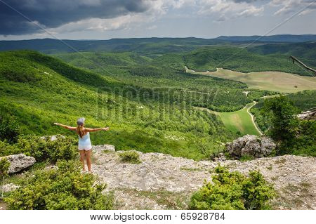 Young woman enjoying the storm at the edge of the cliff, Crimea, Ukraine