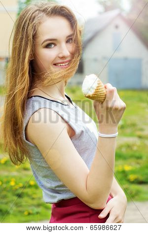 Young attractive smiling girl in a sunny day with an ice cream in the hands of walking around the ci