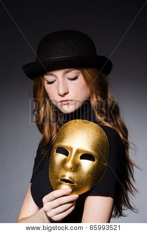 Redhead woman in hat  iwith mask in hypocrisy consept against grey background