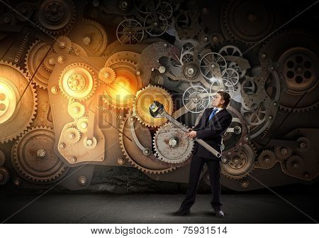 Young businessman fixing gears mechanism with wrench