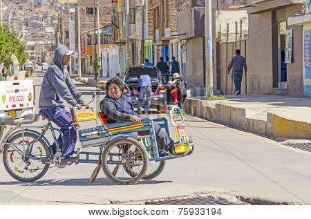 PUNO, PERU, MAY 5, 2014: Pedicab transports local woman  in city center