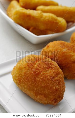 some plates with croquetas and calamares a la romana, spanish croquettes and breaded squid rings, on a set table