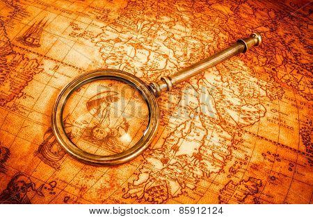 Vintage still life. Vintage magnifying glass lies on an ancient world map in 1565.