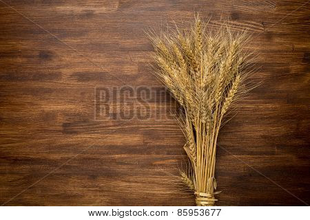 Wheat Ears on the Wooden Table. Sheaf of Wheat over Wooden. Harvest concept