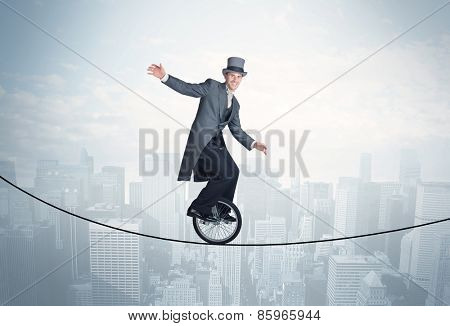Brave guy riding a monocycle on a rope above cityscape concept