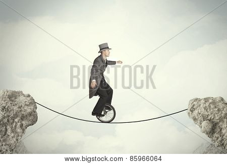 Brave business man riding an mono cycle between cliffs concept
