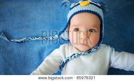 small baby in owl hat on blue background