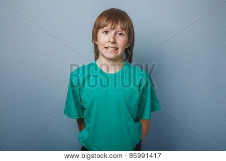 Boy, teenager, twelve years in a green T-shirt , showing teeth