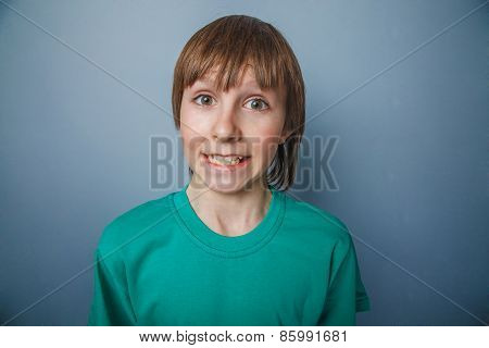Boy, teenager, twelve years in a green T-shirt, showing teeth