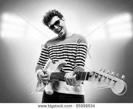 Musician is playing electrical guitar on stage