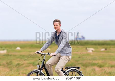 Man having bicycle tour with bike at levee with sheep