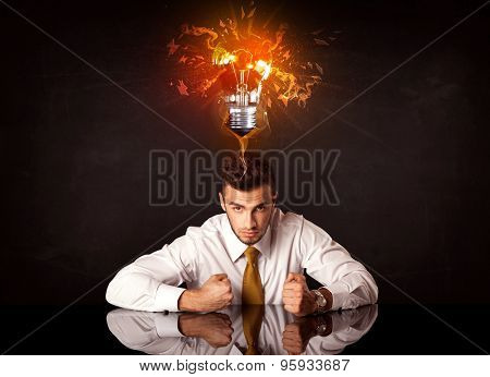 Depressed businessman sitting under a blowing idea bulb
