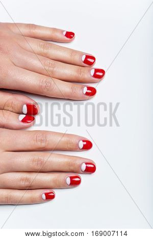 Close-up shot of young femle hands with red and white nail manicure. Copy space.